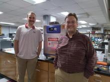 Blake Katz and Dr. Nick Fitzkee stand in front of the heated photothermal irradiation chamber in Fitzkee’s lab. When experiments are in progress, this chamber can be used to irradiate nanoparticles with infrared light and examine the effects.
